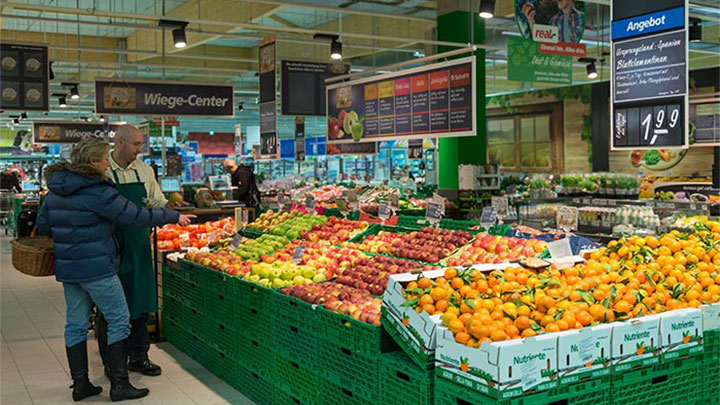 Los clientes miran la fruta en Real iluminada mediante soluciones para supermercados de Philips