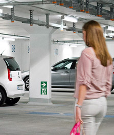 Una mujer se dirige a su coche en un aparcamiento bien iluminado con la solución sostenible Green Parking