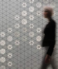 Una mujer pasa junto a un panel interior decorado con patrones luminosos de Philips - experiencia del cliente